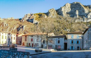 Place du village (mairie & église Saint Jean-Baptiste) (766 m). Rocs Marot et de la Lauzade supportant le château en arrière plan.